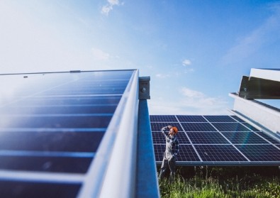 Ingeniero de Sonetel Energía, Conexión y Futuro inspeccionando paneles solares en un campo bajo cielo despejado.